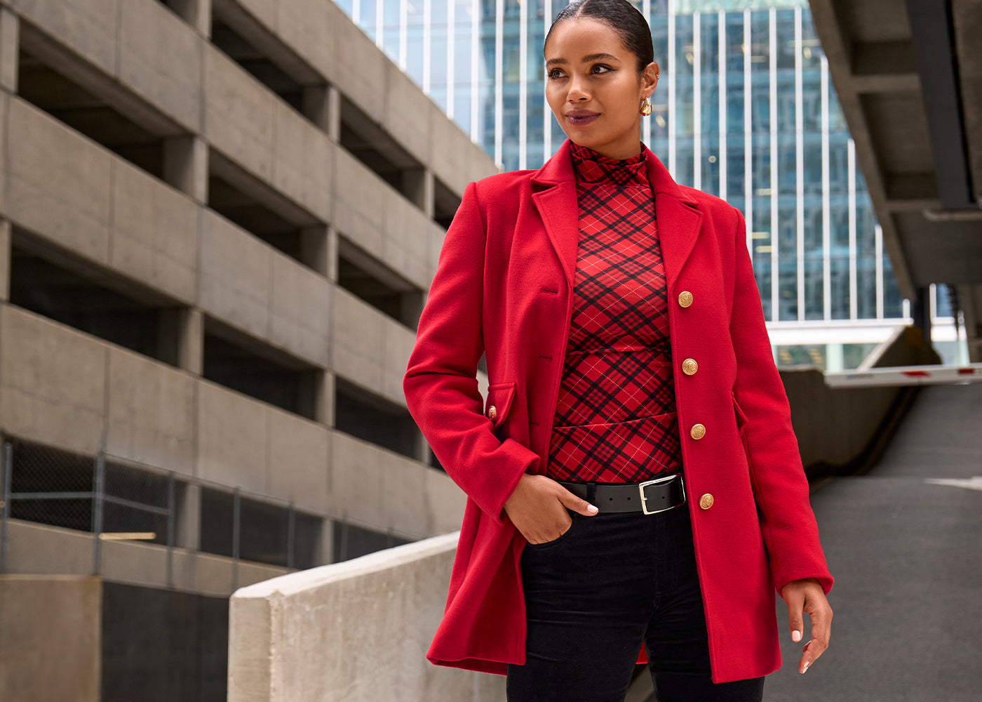 Models wearing a red and black turtleneck top with a red tailored coat and black pants.