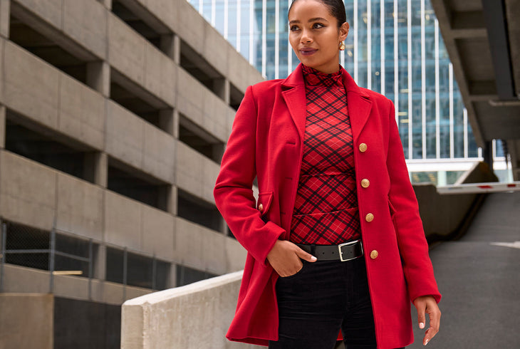 Models wearing a red and black turtleneck top with a red tailored coat and black pants.