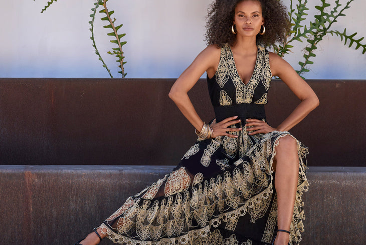 Models wearing a black and gold accent high low dress with black heels.