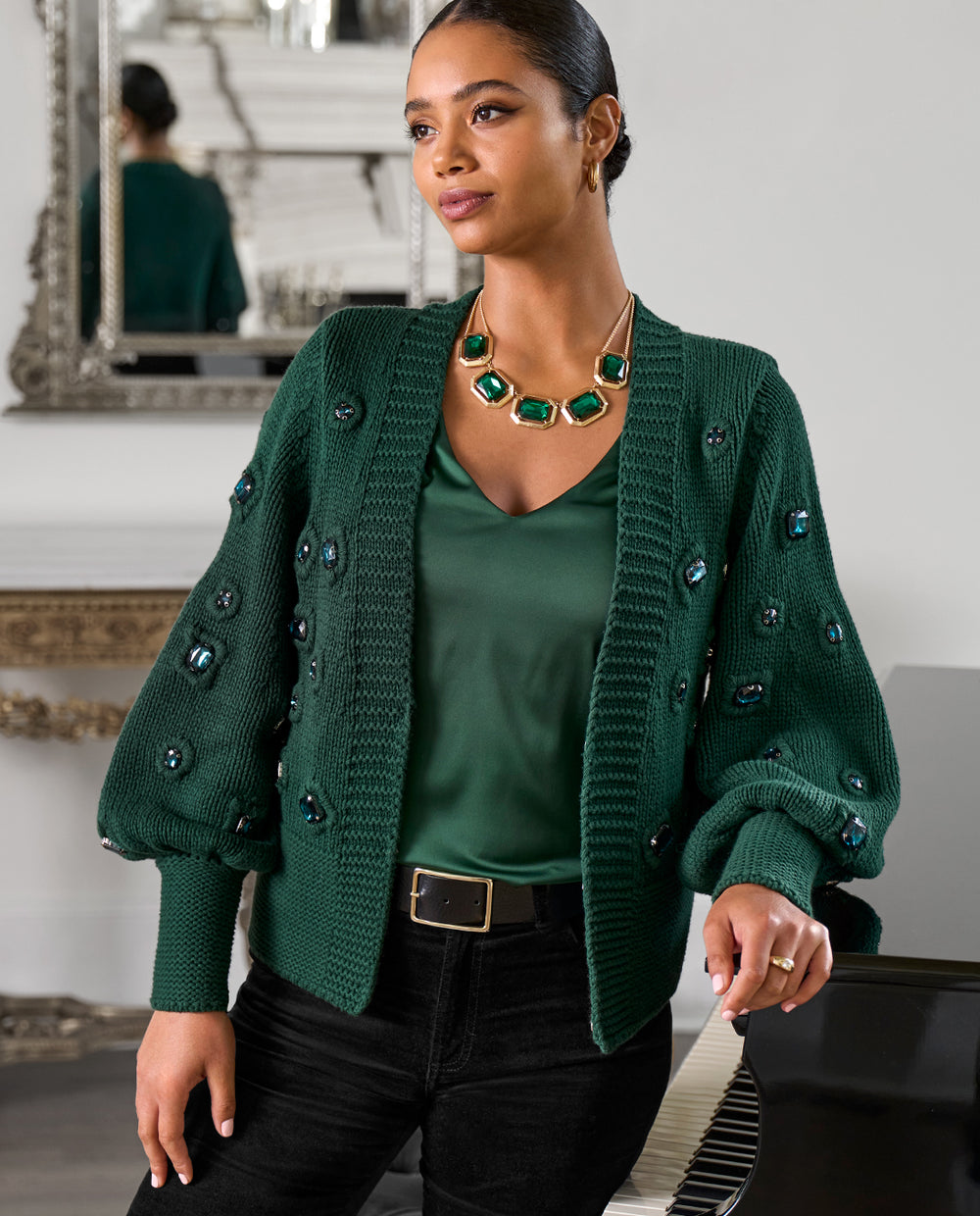 Models wearing a green embellished sweater, green necklace, green nikki top and black pants.